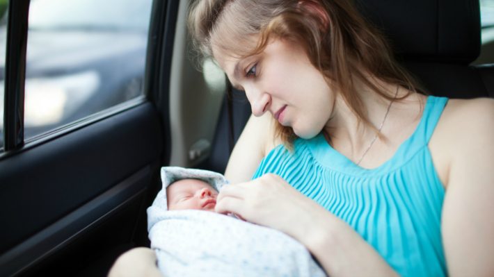 Mother looks gently at infant while travelling in the car